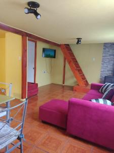 a living room with a purple couch and a tv at Cabaña Hornopiren 1 in Hornopiren