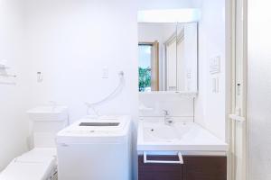 a white bathroom with a sink and a mirror at Manere in Tokyo +74 photos