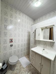 a white bathroom with a toilet and a sink at Pousada Recanto dos Maximianos in Jarinu
