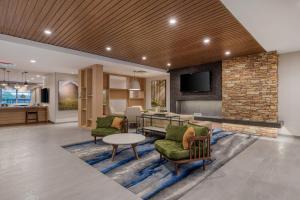 a lobby with chairs and a table and a stone wall at Fairfield Inn & Suites by Marriott Charlotte Belmont in Belmont