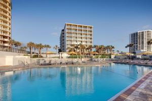 a large swimming pool with chairs and a hotel at Delta Hotels by Marriott Daytona Beach Oceanfront in Daytona Beach