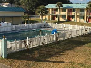 a white fence next to a swimming pool at Garden Inn & Suites in Pensacola