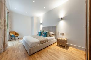 a white bedroom with a bed and a chair at 250 SqM MEGA MANSION in London