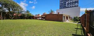 a yard of a building with a grass field at Casa a duas quadras do mar próxima ao centro in Capão da Canoa