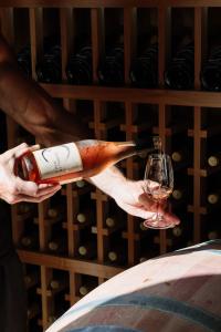 a person holding a bottle of wine and a glass at Barrique Studio with Sauna at Barrelled Wines Raglan in Raglan