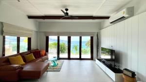 a living room with a couch and a flat screen tv at Villa Amara - Luxury Infinity Pool Villa with Sea view in Surin Beach