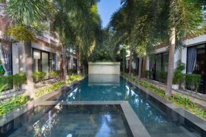 a swimming pool in the middle of a building with palm trees at Tunnel Urban Retreat in Siem Reap