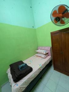 a small bedroom with a bed with a fan on the wall at Lylinz Dy Cermai in Pasir Gudang