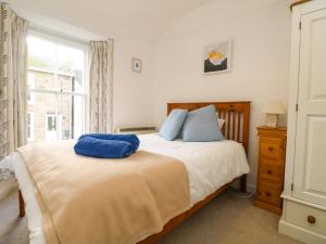 a bedroom with a bed with blue pillows on it at Calac Cottage in Mousehole