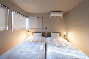 two beds sitting next to each other in a room at Cosmique Chalet Hakuba in Hakuba