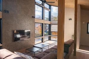 a living room with two couches and a large window at Cosmique Chalet Hakuba in Hakuba
