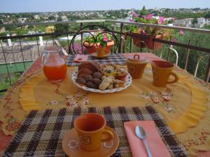 a table with a plate of food and cups of orange juice at B&B Casa Mariangi in Castellana Grotte