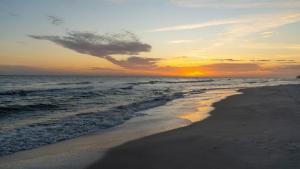 a sunset on a beach with the ocean at Strand Castle - GULF FRONT! An ideal layout with game room, small private pool, and roof top crow's nest! home in Dauphin Island