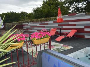 a patio with chairs and a table with flowers and an umbrella at Maison de Ville avec Spa et Sauna près d'Orléans - FR-1-590-547 in Chécy