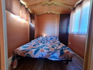 a bed in a small room with a bedspread at Roulotte Bohème Confort au Sud de Nancy - FR-1-584-364 in Burthecourt-aux-Chênes