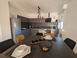 a kitchen with a black table and chairs in a kitchen at Appartement confortable à Épinal, 2 chambres, wifi, parking, petit chien accepté - FR-1-589-766 in Épinal