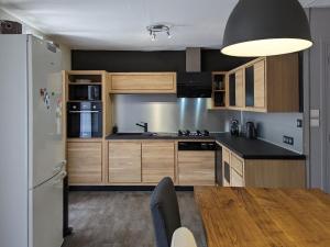 a kitchen with wooden cabinets and a table and a refrigerator at Maison familiale proche châteaux, vélo Loire, parking privé - FR-1-590-551 in Messas