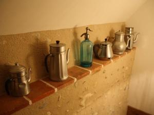 a row of tea pots and a bottle on a brick wall at Gîte charmant sur Loire avec terrasse en nature - FR-1-590-545 in Sully-sur-Loire