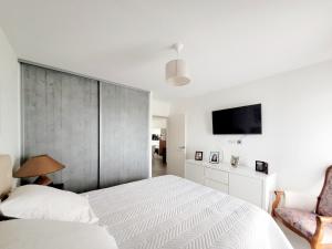 a white bedroom with a large bed and a tv at T3 moderne avec clim et wifi, proche port et mer, box fermé - FR-1-794-157 in Canet-en-Roussillon