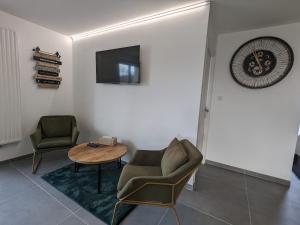 a living room with a chair and a table and a tv at Gîte spacieux près du lac avec spa, aire de jeux, wifi et activités variées - FR-1-589-767 in Chaumousey