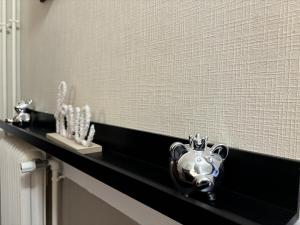 La salle de bains est pourvue d'une étagère noire avec une théière en argent. dans l'établissement Appartement confortable, proche centre-ville, idéal pour 4 personnes - FR-1-489-555, à Moulins