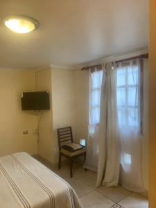 a bedroom with a bed and a window and a chair at Hostal CacTus in Coquimbo