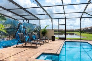 a patio with a pool with chairs and a painting at Modern 5BR TwnHome w Private Pool Near Disney 358 in Kissimmee