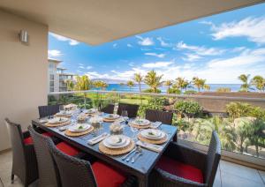 a dining table with chairs and a view of the ocean at Oceanfront Views Above Dukes - Wrap Around Lanai - Outdoor Kitchen Honua Kai H351 in Lahaina