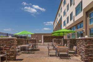 a patio with tables and chairs with green umbrellas at Element Houston Katy in Katy