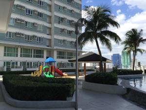 um parque infantil em frente a um edifício com uma palmeira em Studio Unit at The Beacon Makati em Manilla