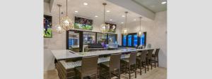 a dining room with a bar with chairs and chandeliers at Modern 5BR TwnHome w Private Pool Near Disney 358 in Kissimmee