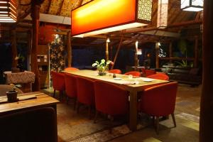 a dining room with a long table and red chairs at Red Coconut Villa in Bentota +200 photos