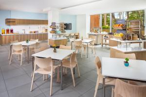 a restaurant with tables and chairs and a kitchen at Element Miami International Airport in Miami