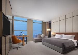 um quarto com uma cama, um sofá e uma televisão em Wanda Yi Hotel Chengdu em Chengdu