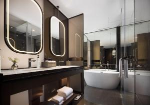 uma casa de banho com 2 lavatórios, uma banheira e espelhos em Wanda Yi Hotel Chengdu em Chengdu mais 43 fotografias