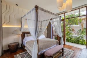 a bedroom with a bed with a canopy at Plawa Laguna Bali - Boutique Hotel & Suites in Canggu