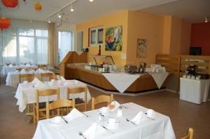 a restaurant with white tables and chairs and a counter at Hotel Karlshof in Karlsdorf-Neuthard