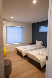 a bedroom with two beds and a window at Koyo Onsen Chalet in Niseko