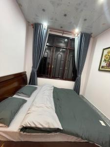 a bedroom with a bed with blue curtains and a window at Home stay Thương Thương in Xuan An