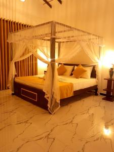 a bedroom with a canopy bed with yellow pillows at Serendib Villa in Ahangama