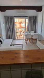 Una sala de estar con mesas y sofás y un balcón. en Perla 5, primera línea de playa y centrico, en Fuengirola