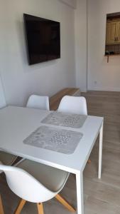 mesa de comedor blanca con 2 sillas y TV en Perla 5, primera línea de playa y centrico, en Fuengirola