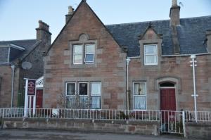 an old brick house with a red door at Jacobite Rose in Inverness