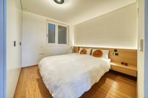 Un dormitorio con una gran cama blanca y una ventana. en Luxury house with panoramic view & hot tub, en Caldaro