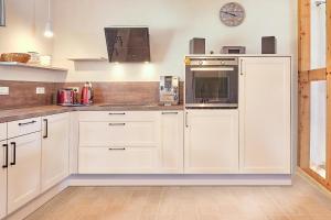 une cuisine blanche avec des armoires blanches et un micro-ondes dans l'établissement Findus, à Fuhlendorf