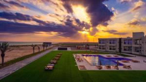 a resort with a pool and chairs and the ocean at Asila Hills Resort in Al Ashkharah
