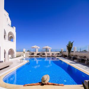 duży basen z osobą leżącą na nim w obiekcie Astir Thira Hotel w Firze