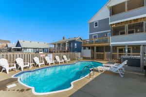 a swimming pool with lounge chairs and a house at 6072 - Barefeat in Nags Head +99 photos