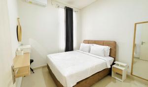 a small bedroom with a bed and a mirror at Villa Ku Villa Mu in Semarang