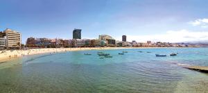 a beach with boats in the water and a city at Green wateratthebeach in Las Palmas de Gran Canaria